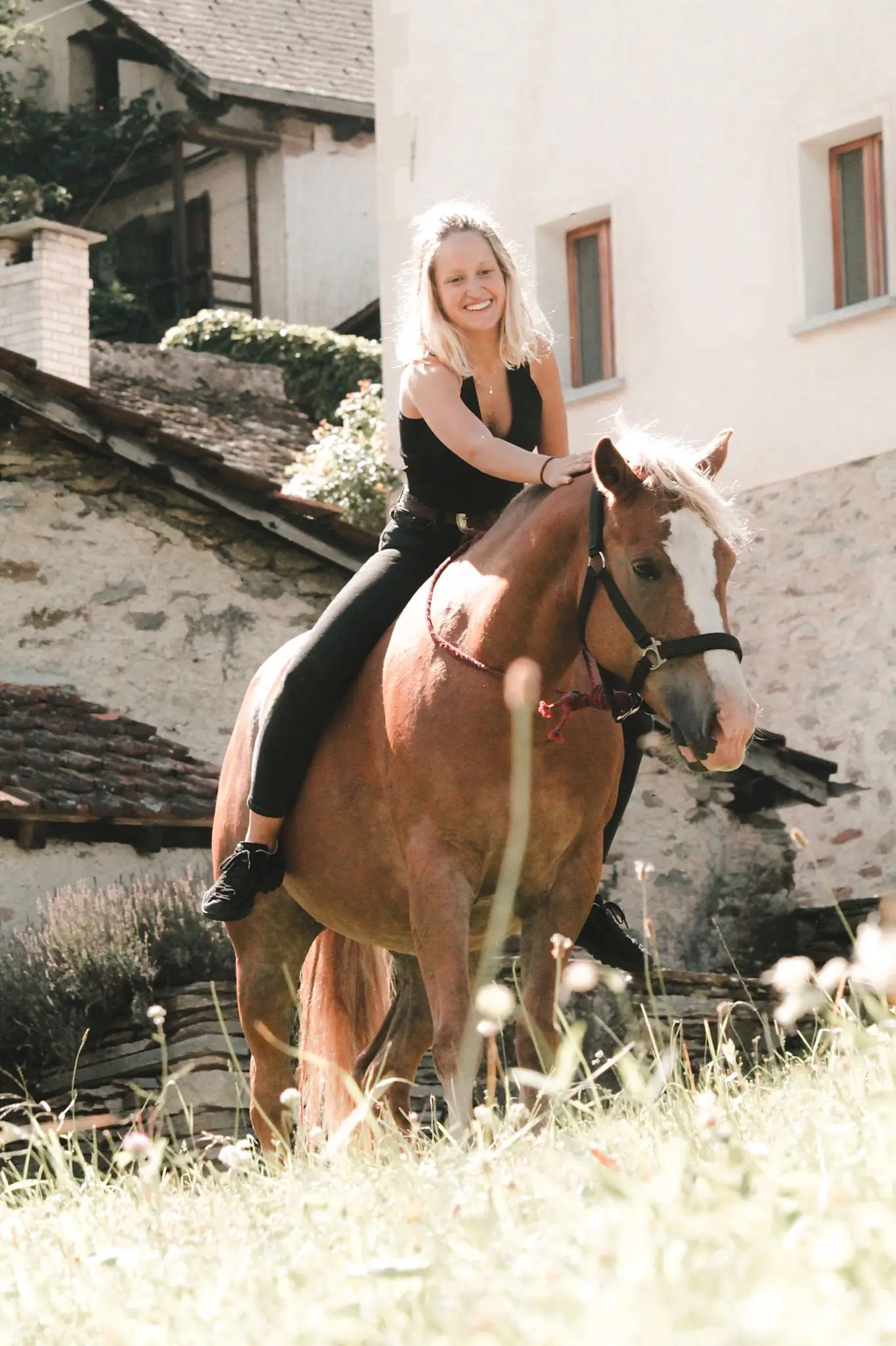 Letizia a cavallo senza sella, sorridente, tra le case di pietra di un paese